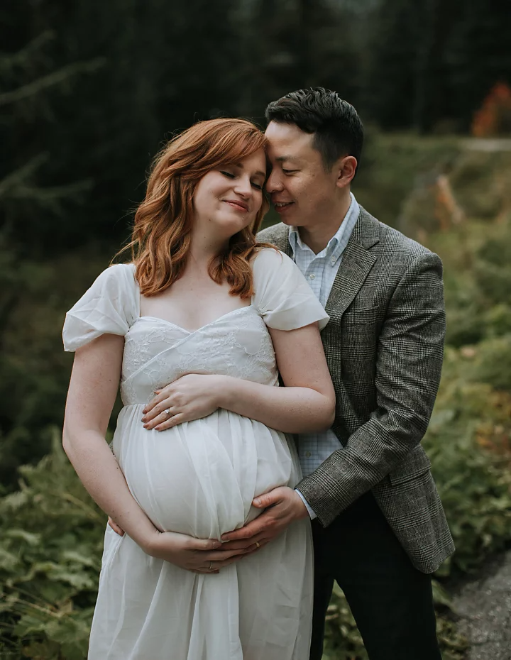 A maternity photo of a couple embracing side by side.