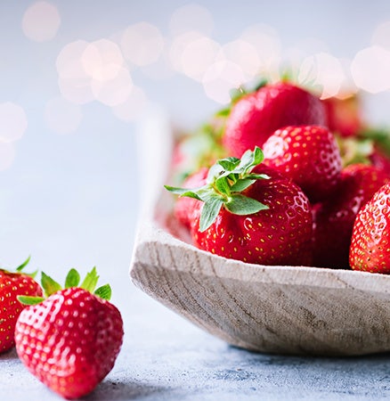 Gros plan sur des fraises dans un bol, avec un effet bokeh en arrière-plan