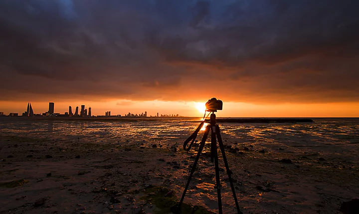 Appareil photo sur un trépied avec un lever de soleil et un paysage urbain en arrière-plan