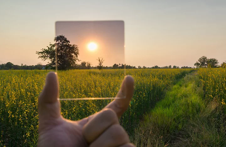 Filtre ND tenu devant le soleil pour atténuer sa luminosité dans une photo de prairie