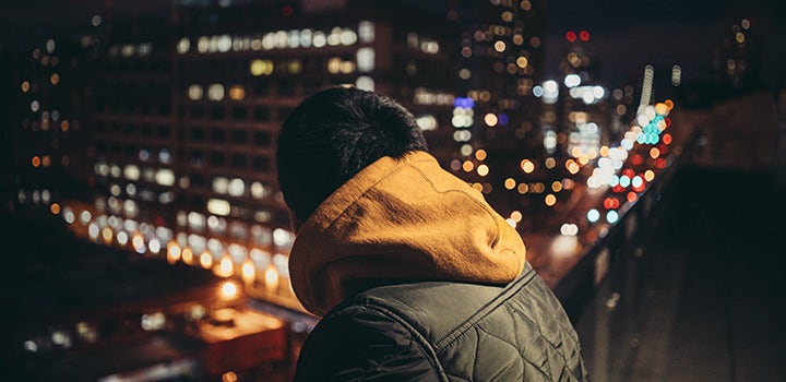 Un homme en ville, de nuit, avec un effet bokeh en arrière-plan