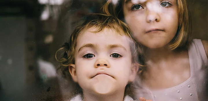 Photo sur le vif de deux enfants le visage collé contre une vitre