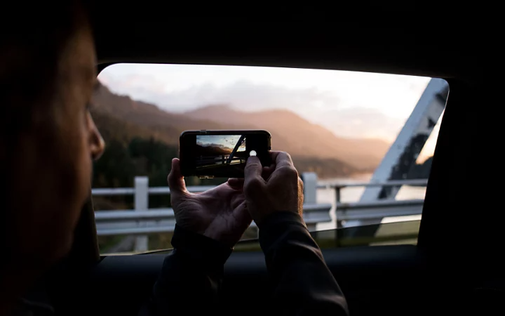 Photo d’une personne prenant une photo avec son smartphone depuis l’intérieur d’une voiture
