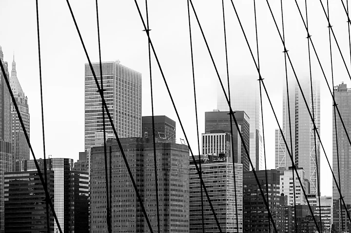 Paysage urbain en noir et blanc photographié à travers les câbles d’un pont