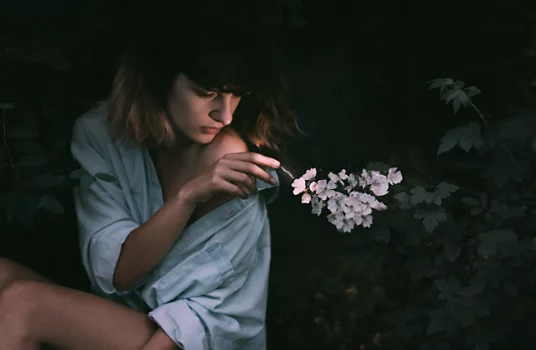 Personne assise qui tend la main pour toucher une fleur à côté d’elle