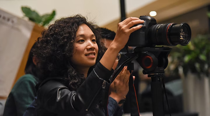 Cinéaste ajustant les réglages de l’objectif de sa caméra pour préparer le plan général