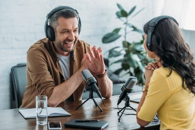 Two people recording a podcast with a glass of water next to them