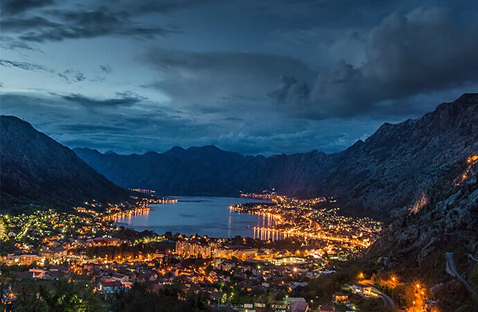 Fotografía de un paisaje nocturno de una ciudad muy iluminada alrededor de una masa de agua
