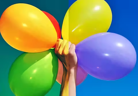 An image of a hand holding balloons. The colours in half of the image are more intense than in the other half., Picture
