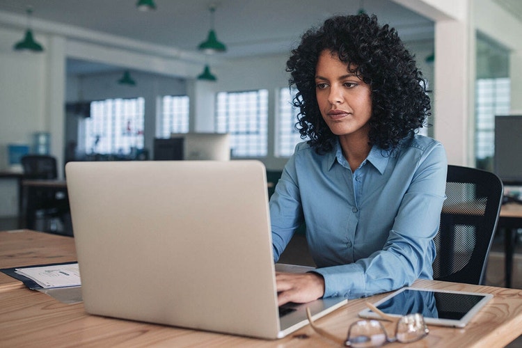 A photo of college students sitting together in a classroom using their laptops