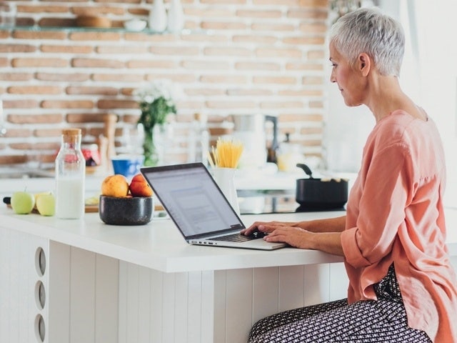 A person sitting at a kitchen island and working on their laptop