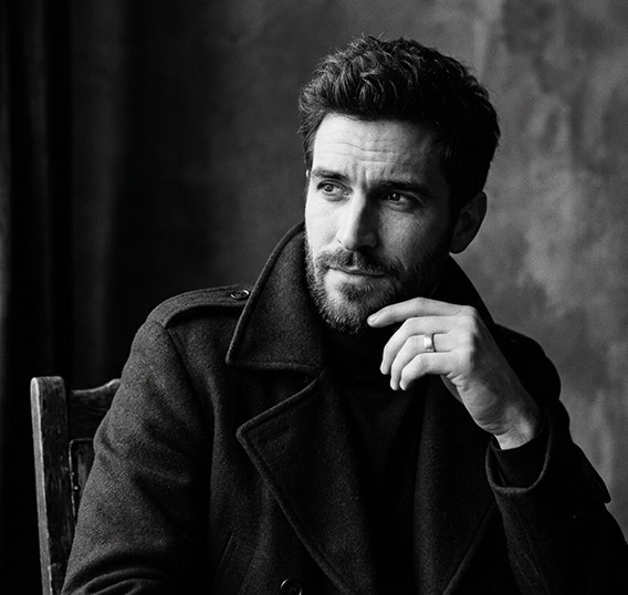 Részletgazdag, MI által generált fekete-fehér kép egy ülő férfiról, aki elgondolkodva néz egy fényforrás felé.