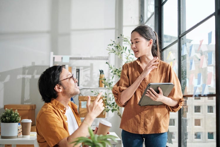 Two young startup partners brainstorming with memo notes in a casual office, planning marketing and e-commerce strategies.