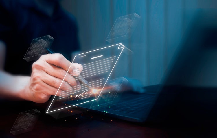 A businessman uses a pen to apply an electronic signature on digital documents displayed on a virtual screen.