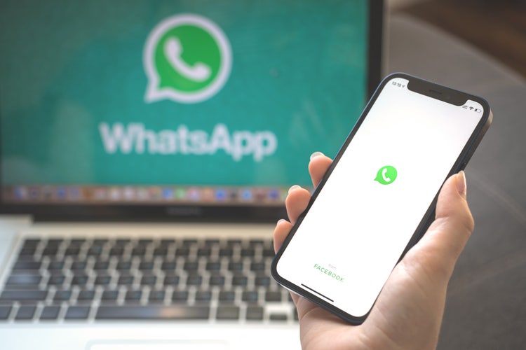 A laptop and a mobile phone showing the WhatsApp logo.