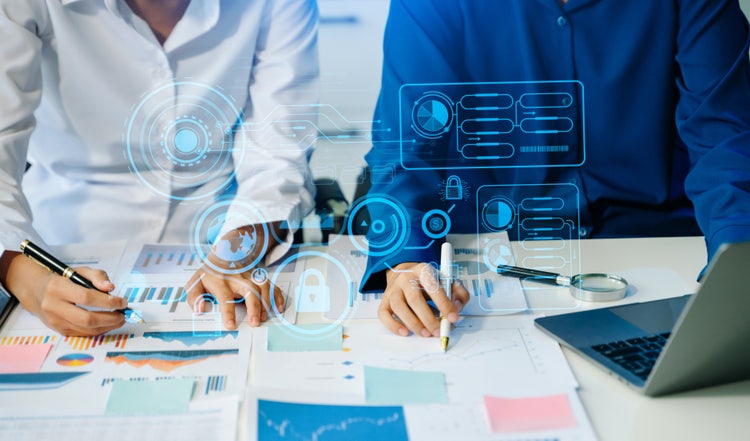 Person using a digital tablet with a holographic interface showing network connections, data icons, and glowing elements on the screen.