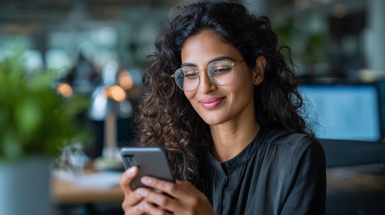 A woman using her mobile phone to manage receipts, invoices, and other financial documents.