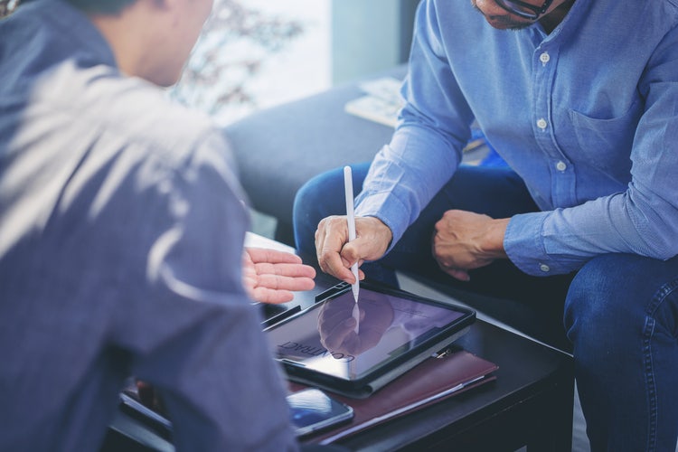 Businessman using digital pen to sign contract on tablet during a meeting.