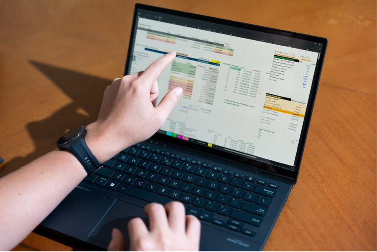 Person working on a detailed spreadsheet with financial data displayed on a laptop screen, preparing to export it as a PDF.