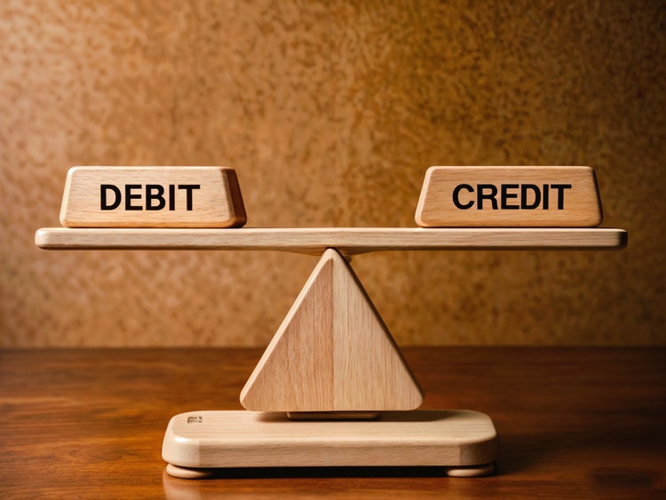Wooden scale with 'Debit' and 'Credit' text on each side, balanced equally, representing the accounting concept of debit and credit rules.