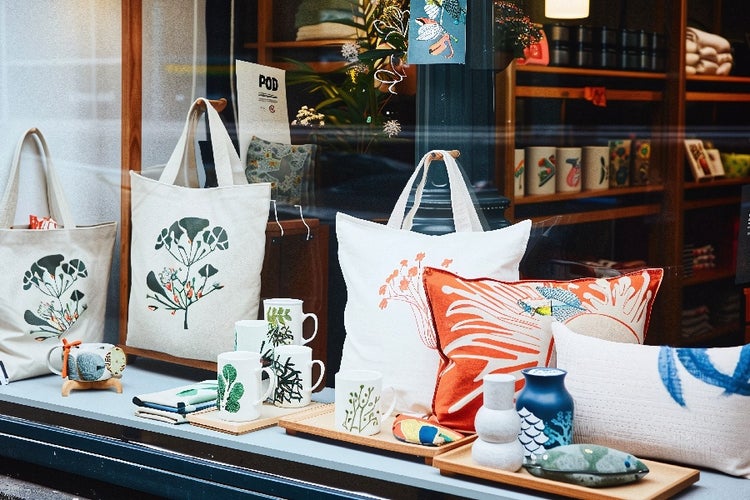 Print-on-Demand (POD) shop window showcasing custom bags, personalized mugs, and decorative home cushions.