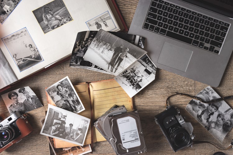 Vintage family photos and album with camera and notebooks on wooden background.