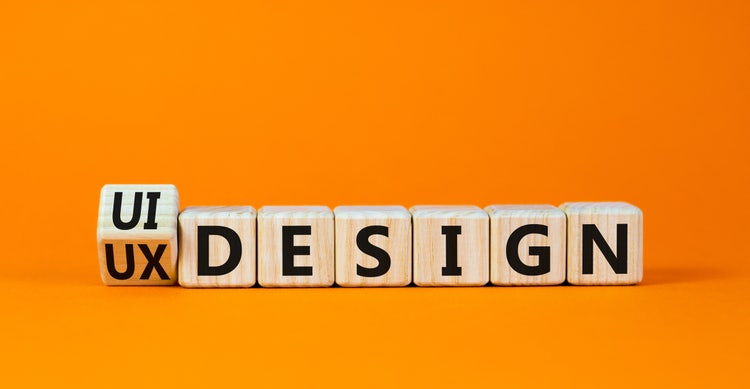UI/UX designer concept with wooden blocks spelling design on orange background.