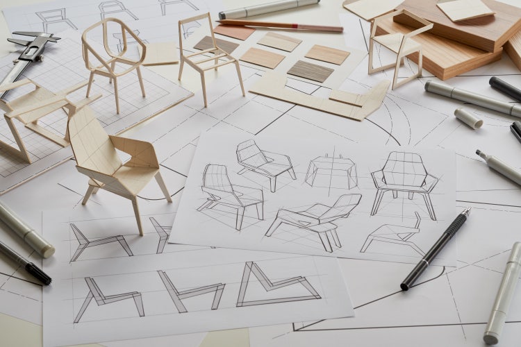 Initial sketches of a chair design, along with 3D models, pens, rulers, and other design tools.