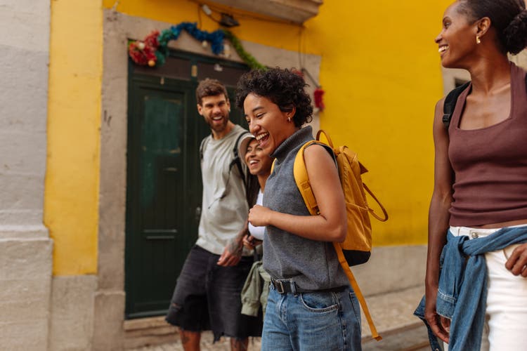 Tourists walking and laughing in Lisbon, Portugal, with shallow depth of field highlighting the lively street scene.