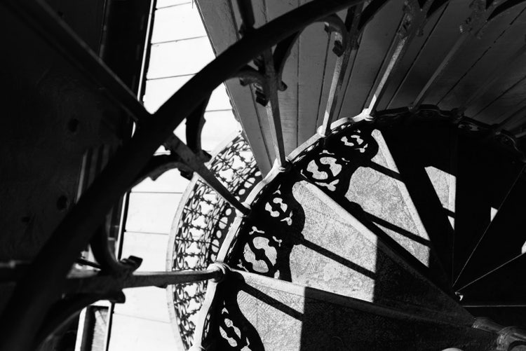 Black and white photograph of a spiral staircase taken with architectural elements and interesting composition.