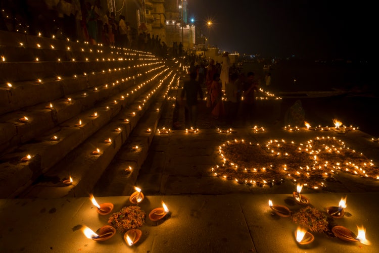 Long exposure night shot of Dev Deepawali celebrations, showing glowing candles and devotees honoring Kartik Poornima.