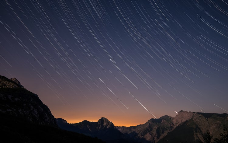 Sunset sky with star trails captured in a long exposure, creating dynamic circular motion.
