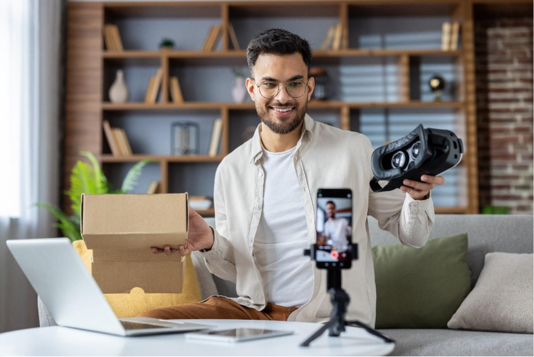 Content creator filming an unboxing video for MKV video production, showcasing a VR headset with a smartphone camera setup.