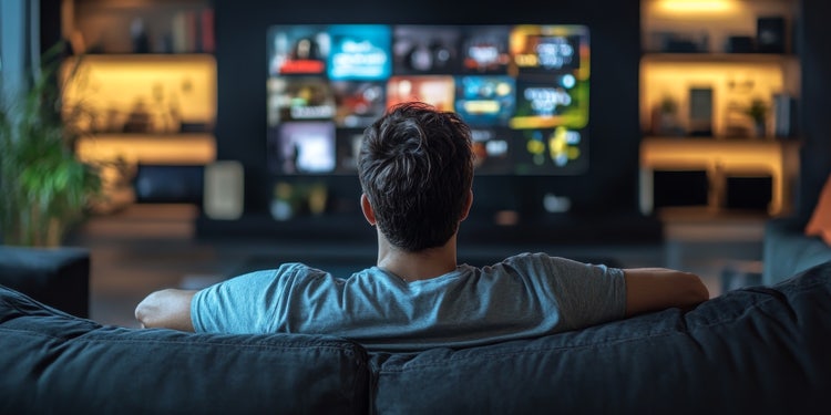 Casual man relaxing on a sofa watching video-on-demand content, illustrating comfort and digital media consumption in modern video format.