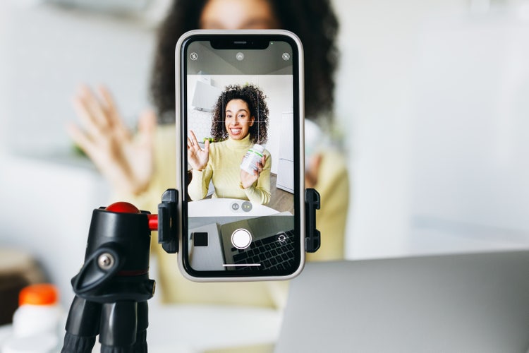 Content creator filming a vertical video on a smartphone, showcasing mobile-friendly aspect ratio setup for social media platforms.