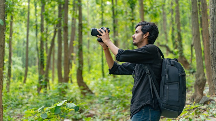 Young photographer in nature using a professional camera for B-roll video capture.