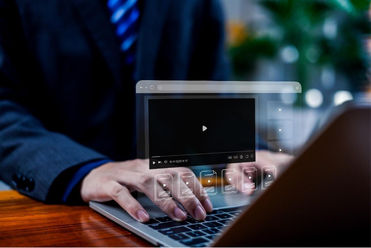 Hands typing on a laptop keyboard with an inset of a floating video player and multiple video files.