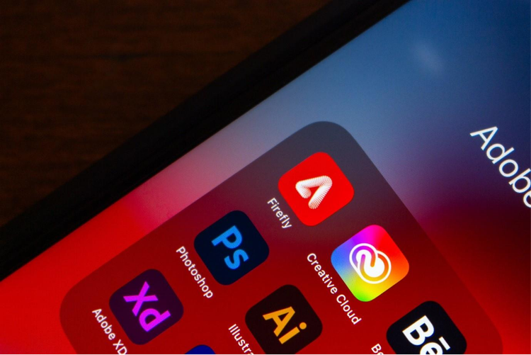 iPhone screen showing Adobe Firefly and Adobe Creative Cloud app icons for creative design tools.
