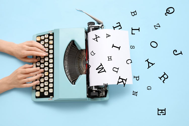 A pair of hands typing on a typewriter with a blank paper sheet on a light blue background and random letters floating around.