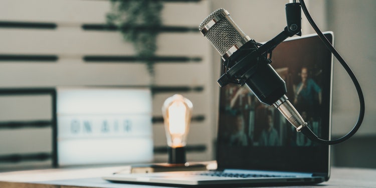 AI dubbing setup with professional microphone, laptop, and on air sign on desk.