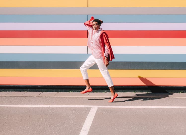 Woman posing with colourful strips in the background, demonstrating beginner-friendly design techniques in Photoshop