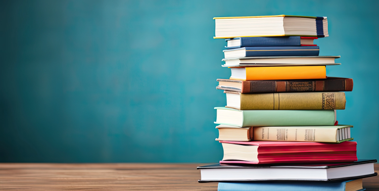 Pila di libri accademici su scrivania in legno e sfondo azzurro.