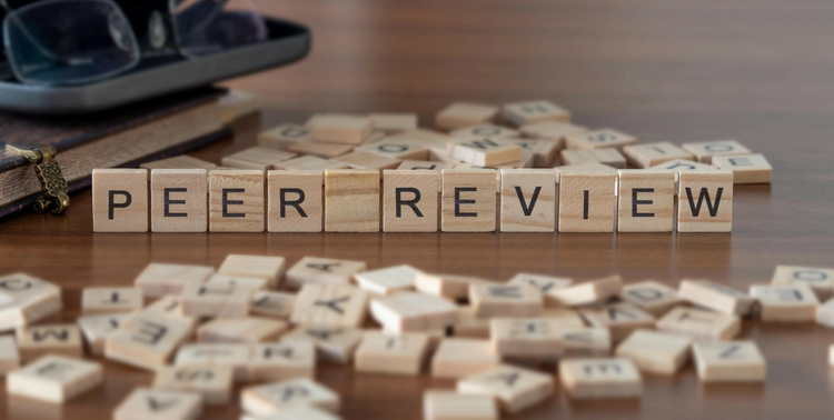 Tessere in legno con lettere che formano le parole peer review