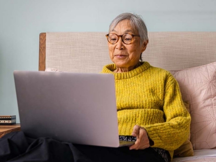 Una persona seduta sul letto che converte una pagina web HTML in un file PDF sul proprio computer portatile.