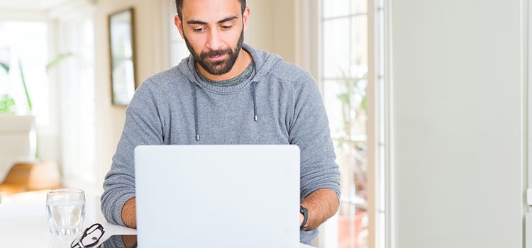 Un uomo seduto alla scrivania con un laptop.