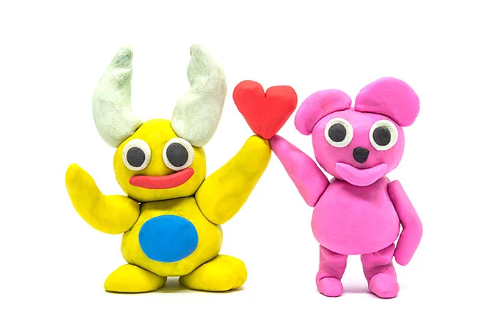 Two colourful clay animals holding a heart between them.