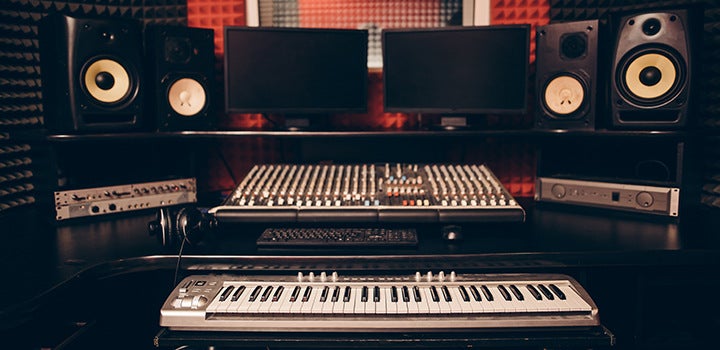 Studio di registrazione con attrezzatura audio e pianoforte.