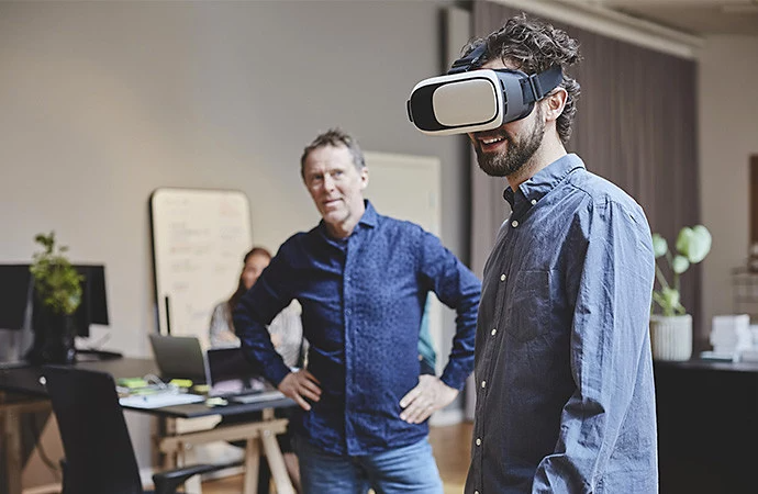 Un uomo che indossa un dispositivo per la realtà aumentata mentre altre persone osservano