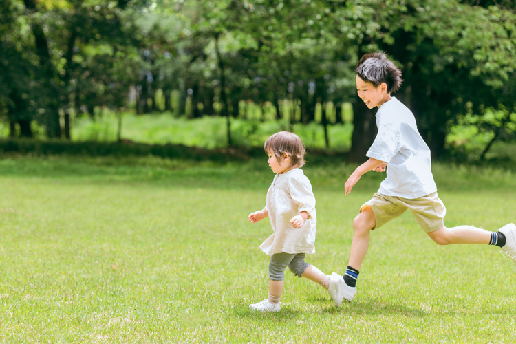 芝生を走る幼子と青年