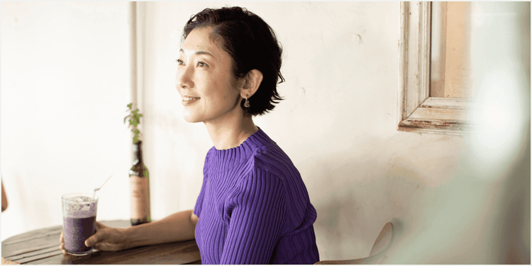 紫のセーターを着て、紫のドリンクをにぎる女性